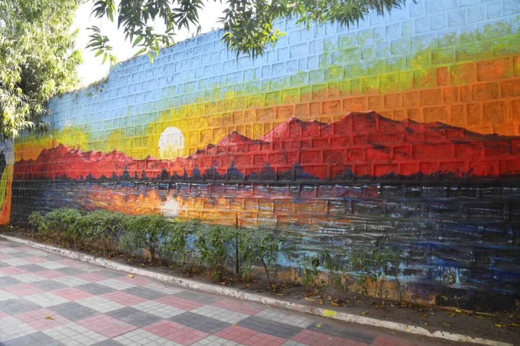 Painted wall mural of a sunset over hills beside a tiled pavement