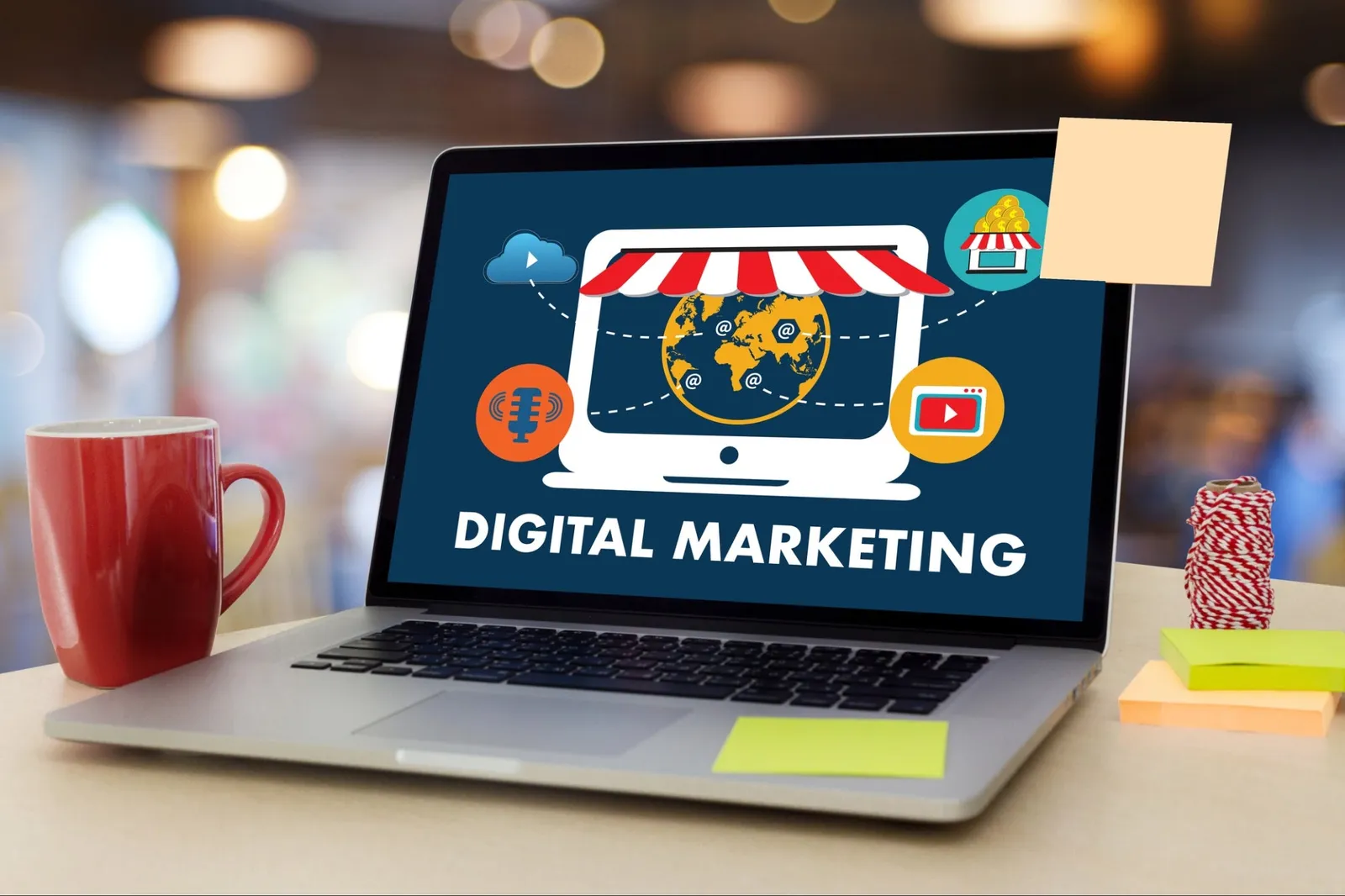 Laptop on a desk showing a digital marketing graphic, with a red mug beside it