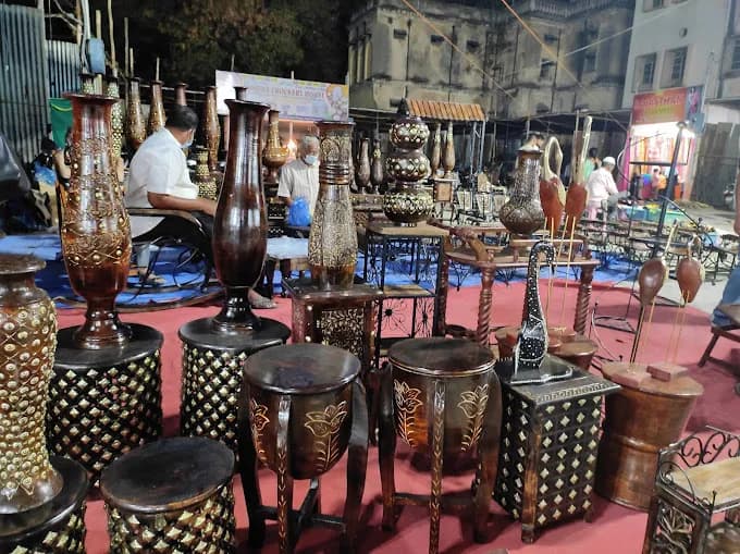 Market stall displaying ornate metal vases, lamps and stools on a street