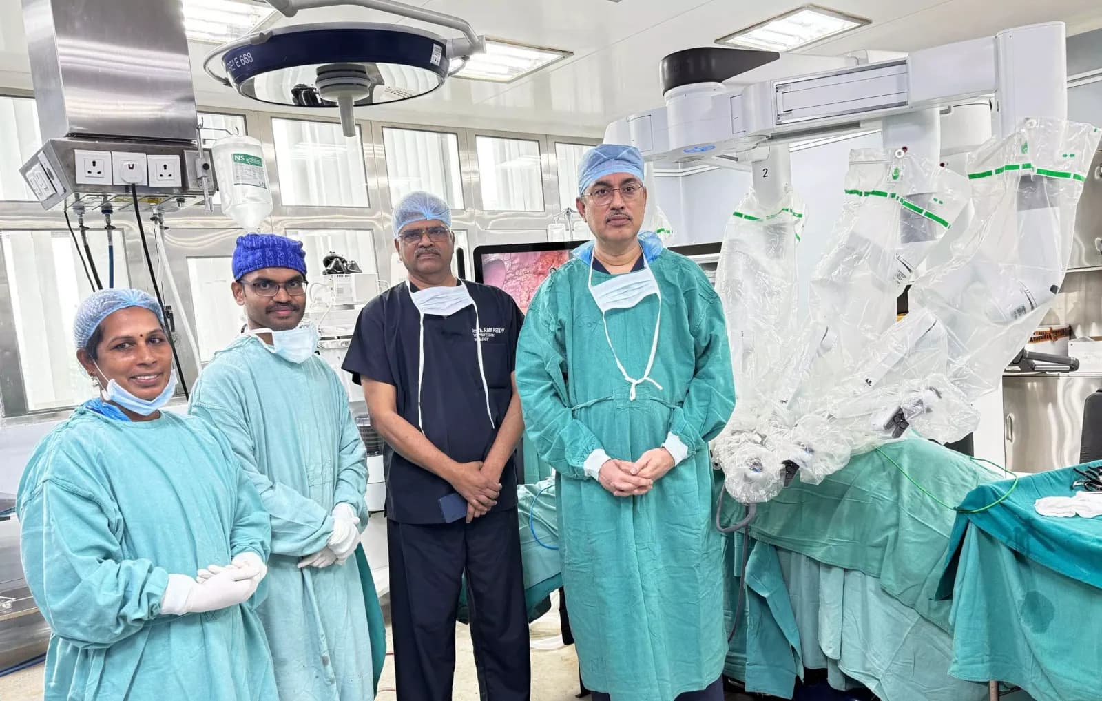 Medical team in surgical gowns and caps standing beside theatre equipment