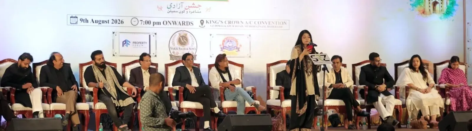 Panel of people seated on a stage with a speaker at a lectern