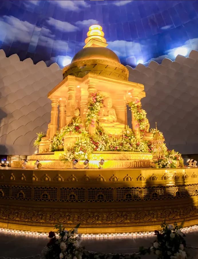 Ornate gilded temple structure lit up at night under a decorated canopy