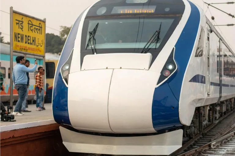 White and blue high-speed train at a station platform beside a signboard