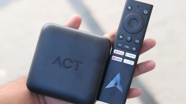 Hand holding a small set-top box and a television remote control