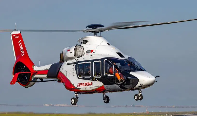 Red and white helicopter in flight above water