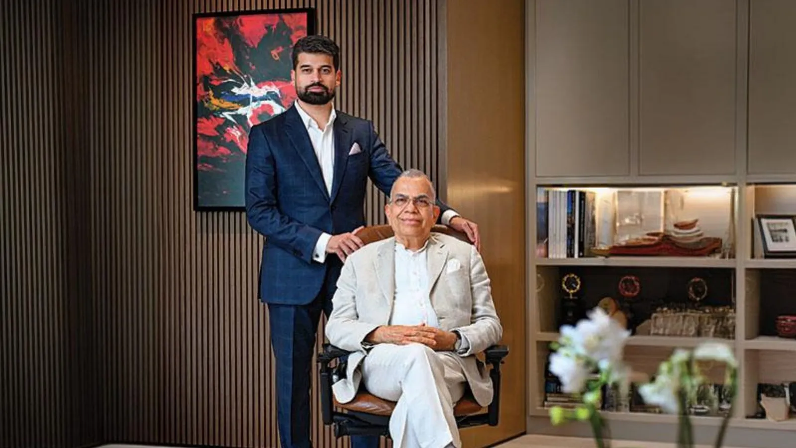 Two men in formal dress posed in a wood-panelled room with shelving