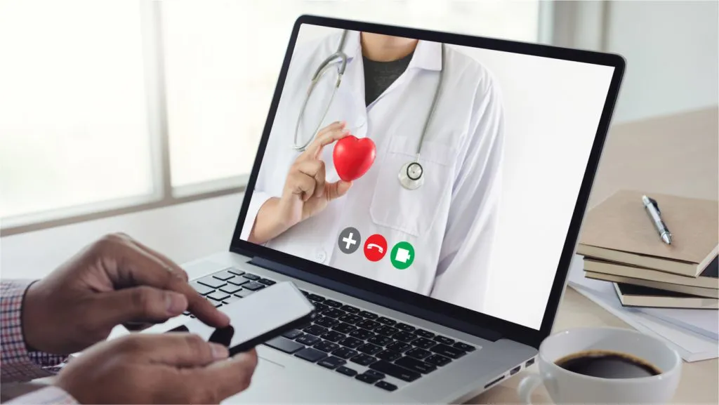 Laptop screen showing a person in a white coat, hands typing on the keyboard