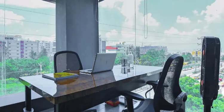 Empty office room with a long desk, wheeled chairs and windows onto a road