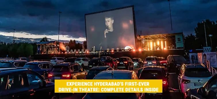 Cars parked before a large outdoor cinema screen at dusk