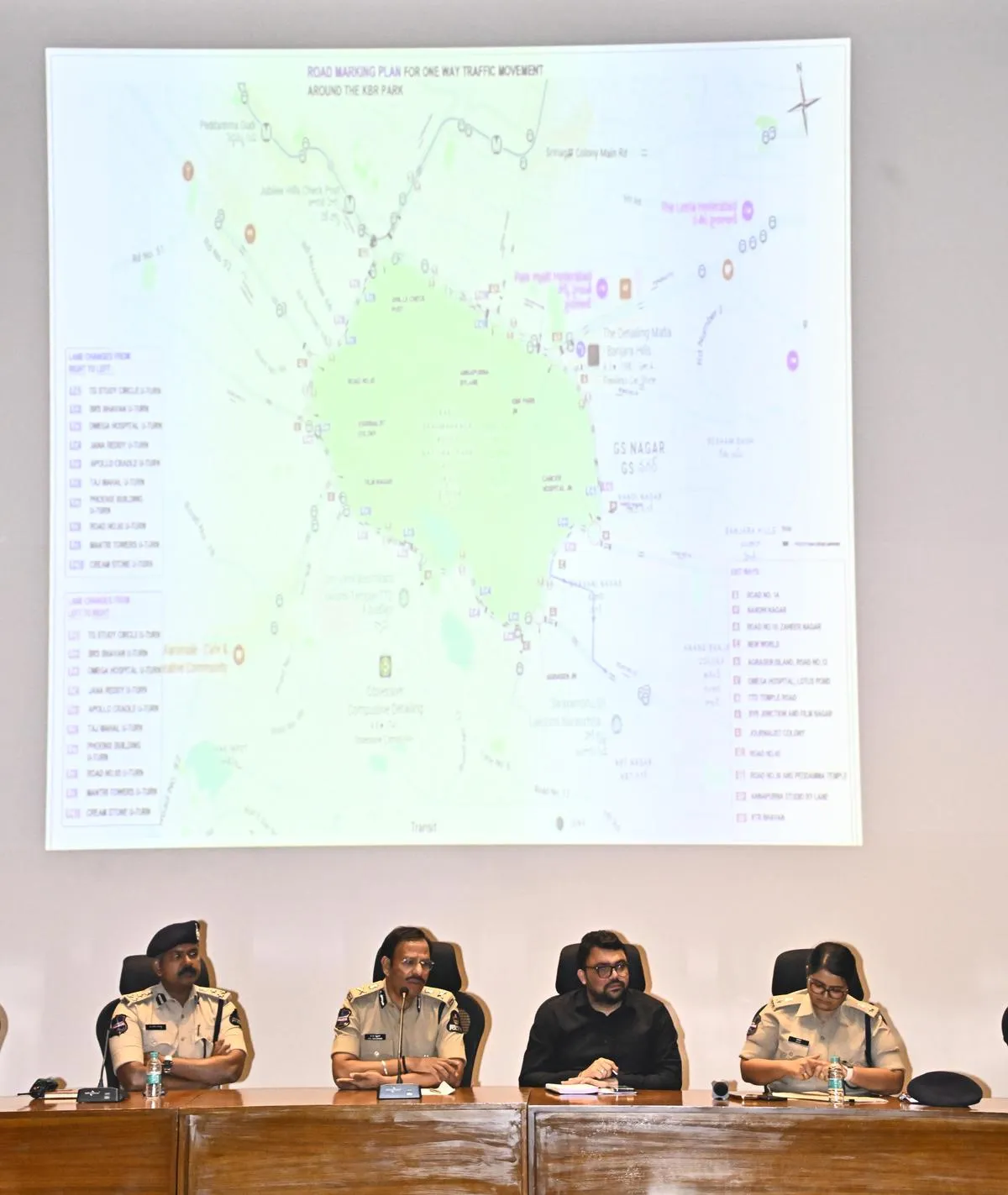 Officials seated at a table before a projected map