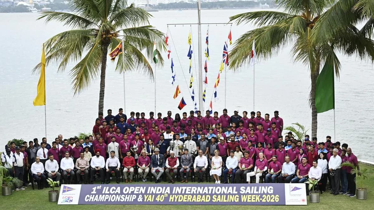 Large group photograph of a sailing squad beside a lake with flags