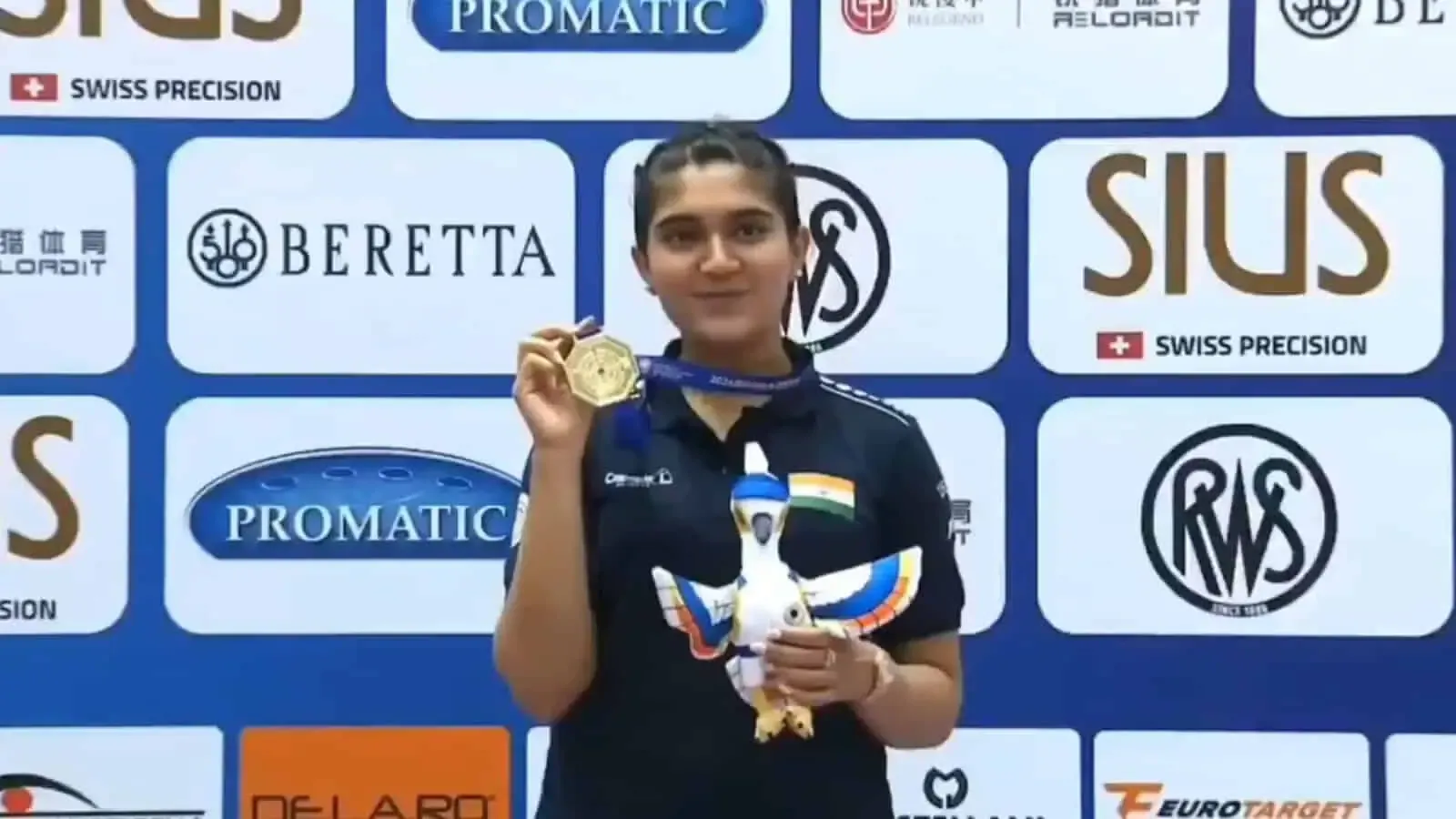 Athlete holding up a medal before a wall of sponsor logos