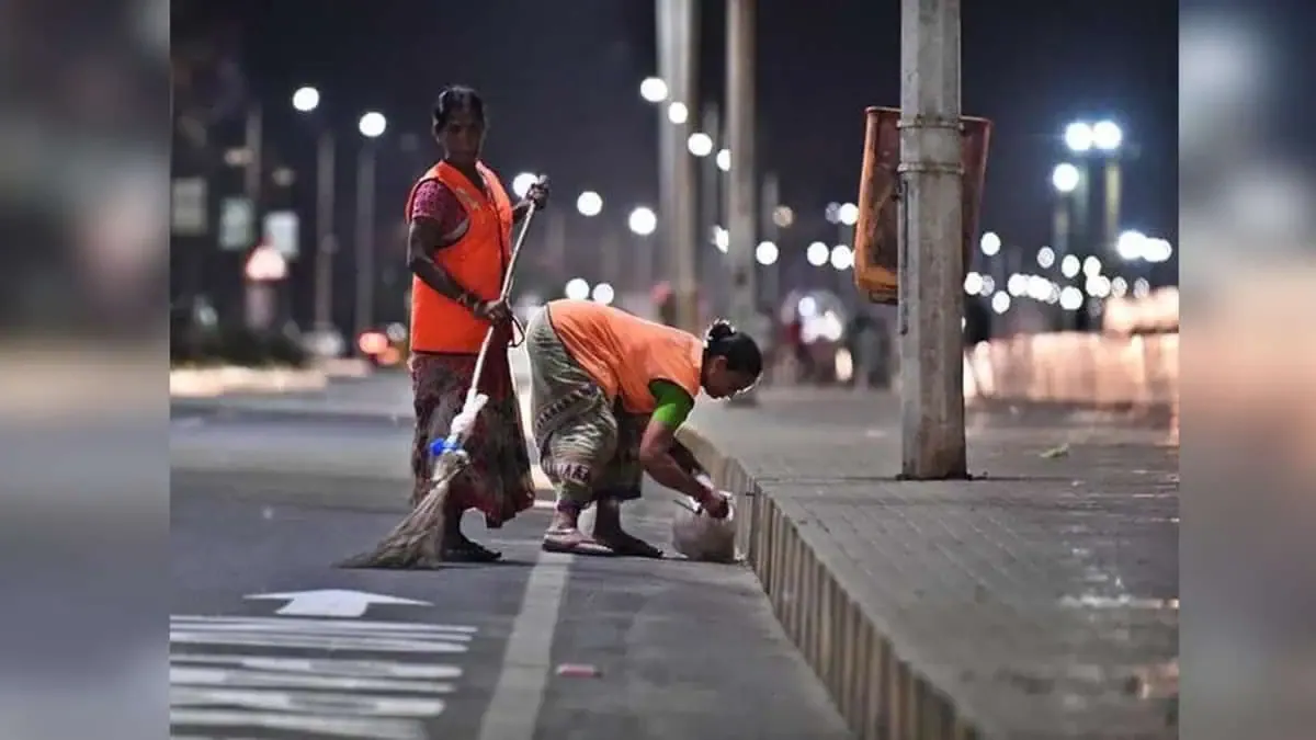 Workers sweeping a lit road at night