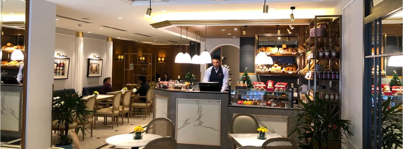 Interior of a bakery cafe with counters, seating and pendant lights