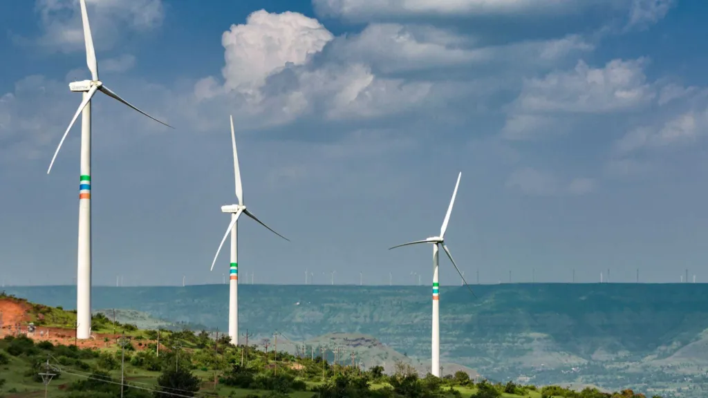 Three wind turbines on a green coastal headland above the sea