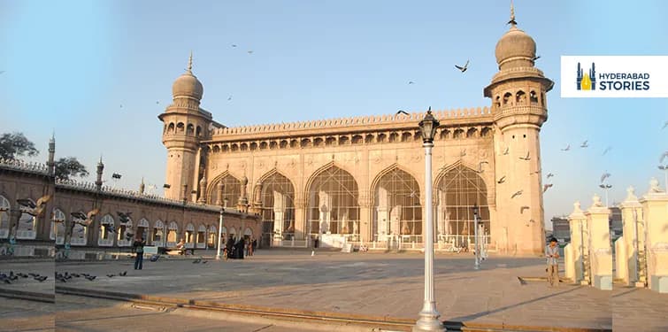 Large arched mosque courtyard with pigeons in flight