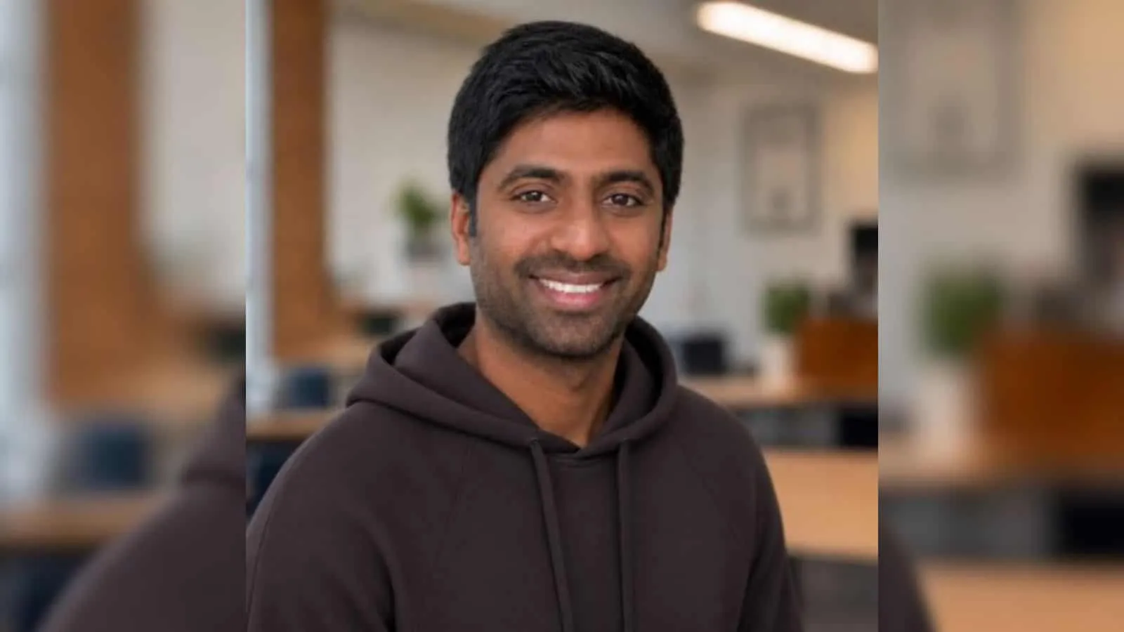 Smiling man in a hooded top in an office