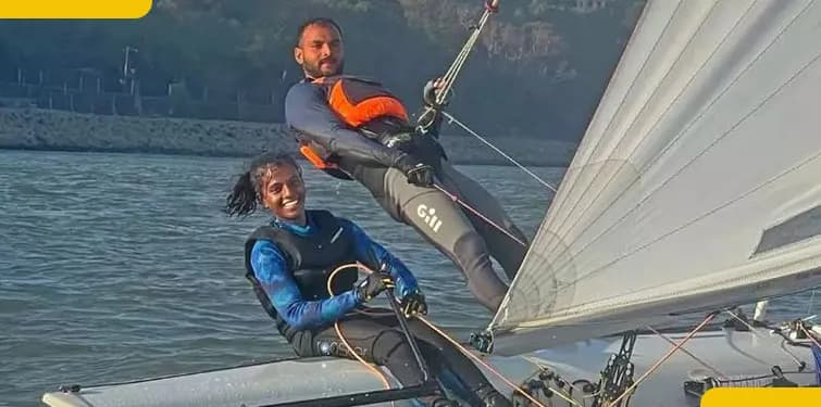 Two people leaning out on a sailing dinghy