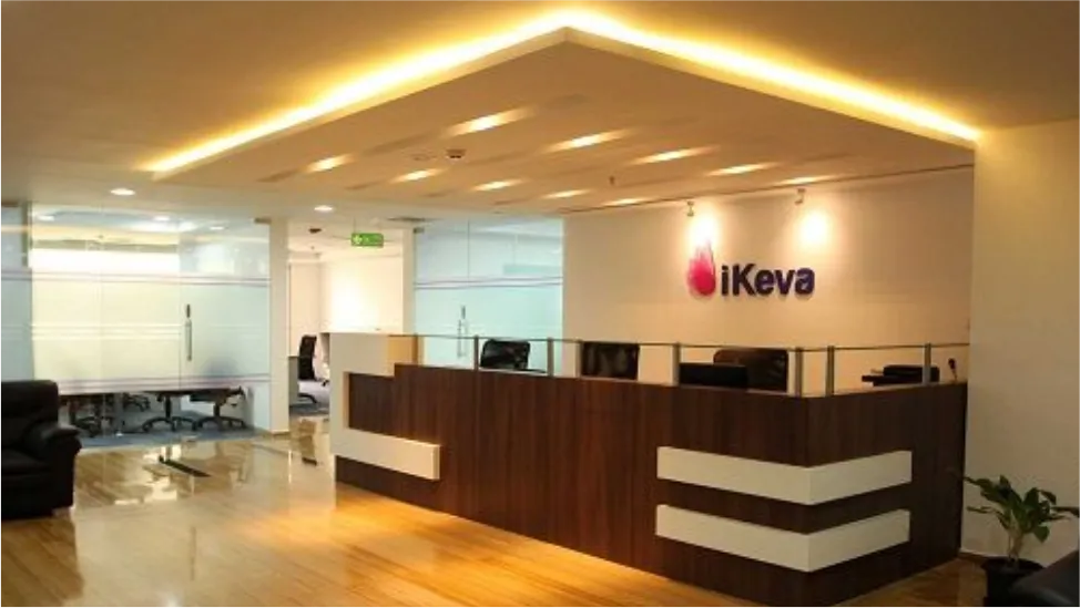 Office reception desk with a lit ceiling panel and a wall sign reading iKeva
