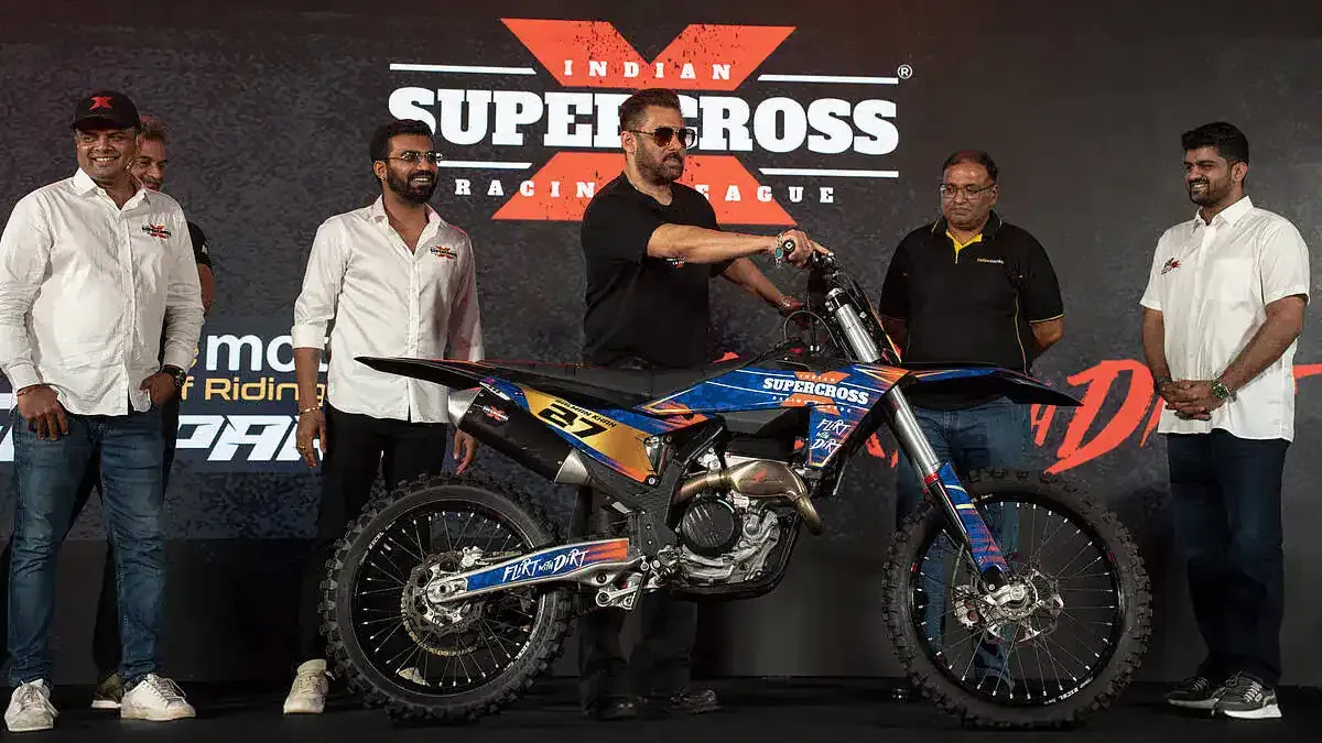 People on a stage beside a motocross bike at a launch