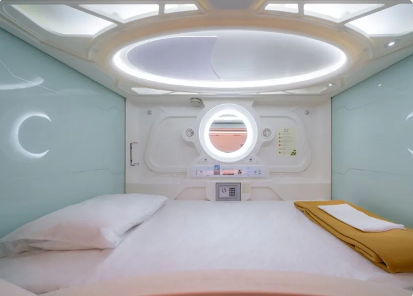 Interior of a compact sleeping pod with a bed and round window