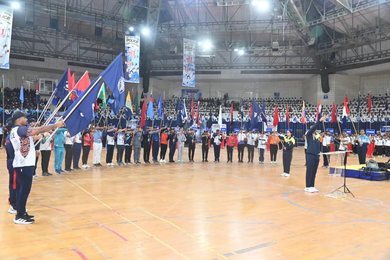 Uniformed teams parading with flags in a large indoor arena