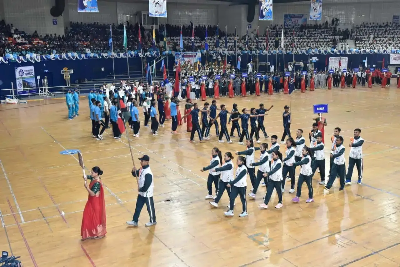Performers in formation on an indoor arena floor before spectators