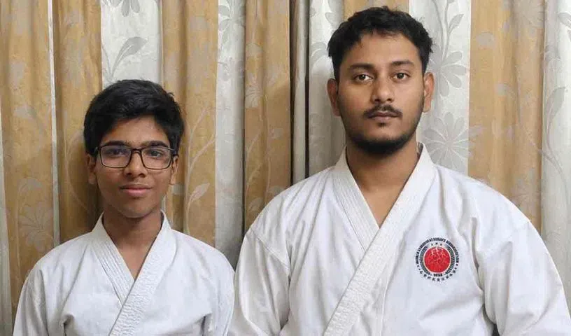 Two people in martial arts uniforms standing indoors