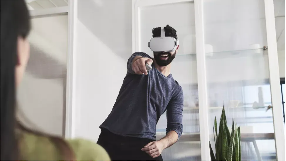 Person wearing a virtual-reality headset with a controller raised in an office