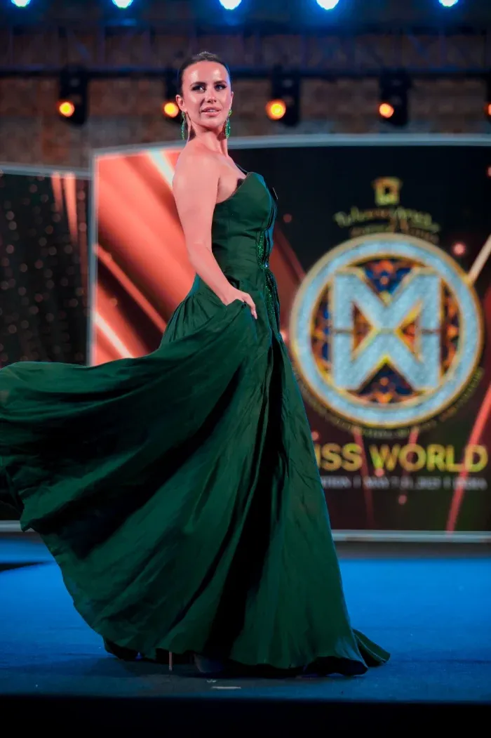 Woman in a long green gown on a lit stage