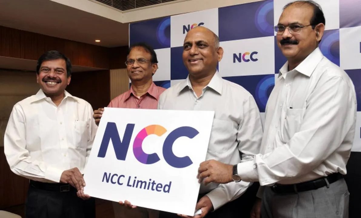 Four men in formal shirts holding a placard reading NCC Limited at an indoor event