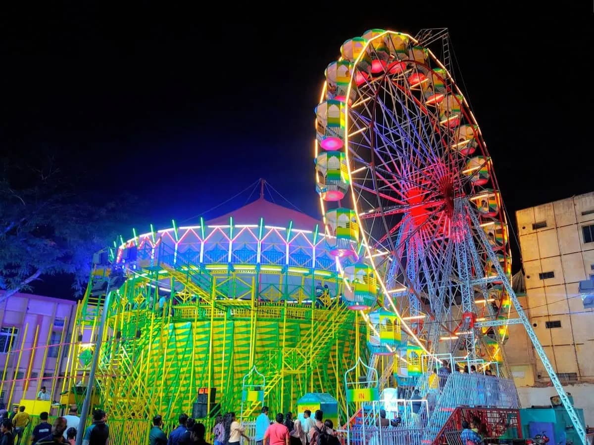 Illuminated fairground ferris wheel and rides at night