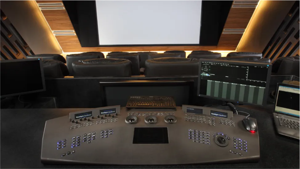 Control room with a large screen facing a tiered console of switches and monitors