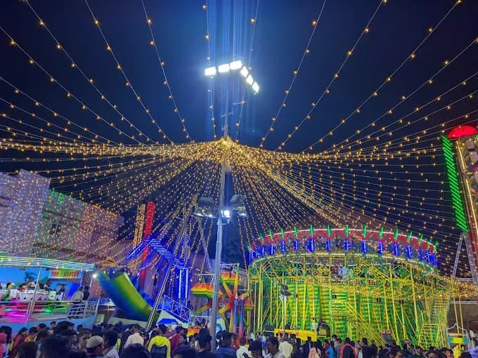 Illuminated fairground canopy of lights at night above a crowd