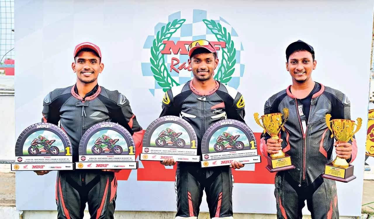 Three racers holding trophies on a podium