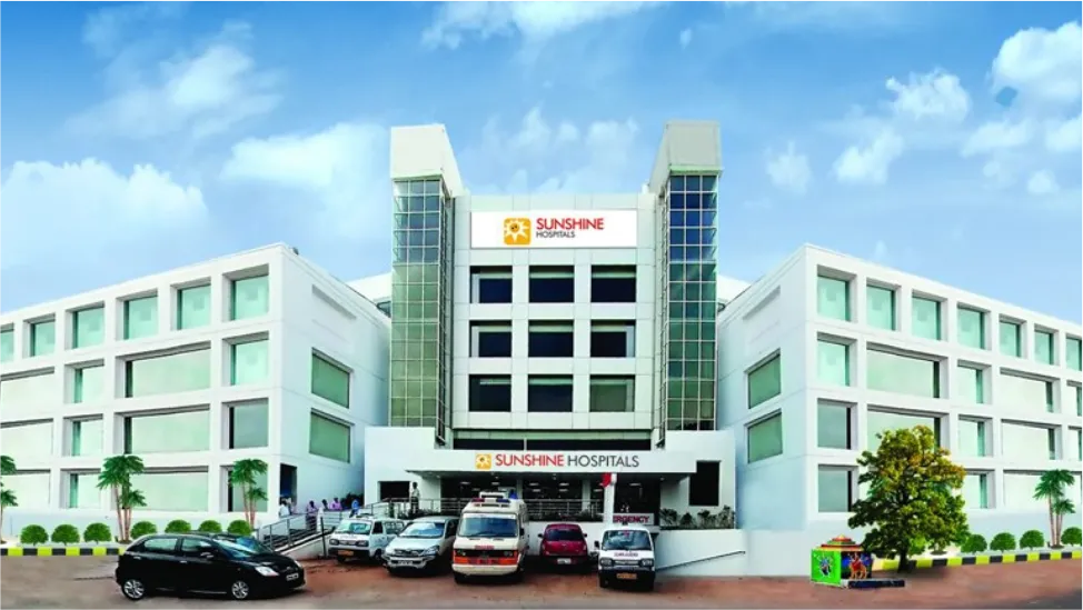 White multi-storey hospital building with ambulances and cars parked outside
