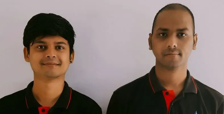 Two people in dark uniforms against a plain background