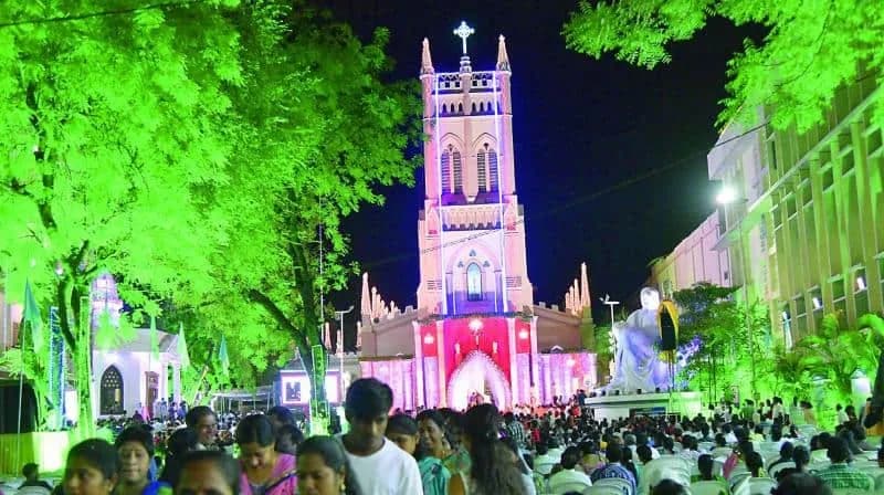 Church lit in pink and green at night with a crowd outside