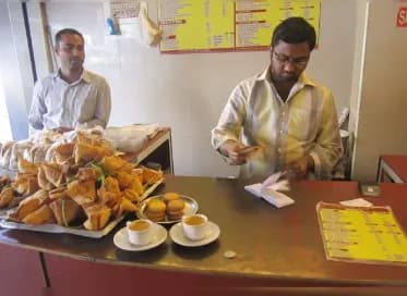 Men preparing snacks behind a counter with plates of food
